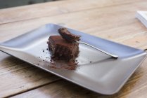 Полусъеденный шоколадный торт на тарелке вилкой — стоковое фото
