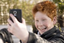 Хлопчик використовує смартфон, щоб взяти селфі — стокове фото