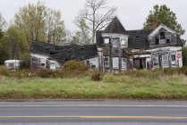 Фасад заброшенного сожженного дома на дороге — стоковое фото