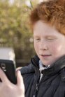 Хлопчик використовує смартфон на відкритому повітрі — стокове фото