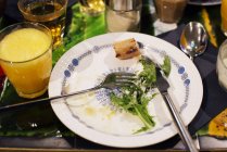 Закрыть наполовину съеденный зеленый салат со столовыми приборами — стоковое фото