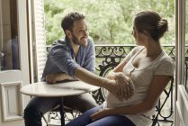 Муж с животом беременной жены сидит за столом — стоковое фото