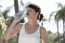 Женщина пьет бутилированную воду на открытом воздухе — стоковое фото