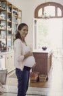 Pregnant woman holding hands on the stomach at home — Stock Photo