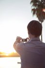 Mann fotografiert Sonnenuntergang mit Smartphone — Stockfoto