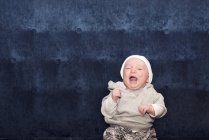 Portrait of crying Baby sitting on the couch — Stock Photo