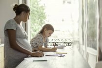 Mother watching daughter coloring with  felt tips at home — Stock Photo