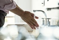 Abgeschnittenes Foto von Mann beim Händewaschen im Waschbecken des Badezimmers — Stockfoto