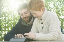 Батько і син дивляться на цифровий планшет разом — стокове фото