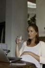 Mujer embarazada sosteniendo un vaso de agua de la casa - foto de stock