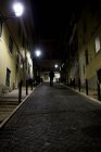 Homem andando na rua de paralelepípedos à noite — Fotografia de Stock