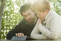 Vater und Sohn schauen gemeinsam auf digitales Tablet — Stockfoto