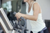 Foto recortada de la mujer utilizando la máquina de ejercicio en el club de fitness - foto de stock