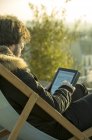 Чоловік використовує цифровий планшет на відкритому повітрі, сидячи в кріслі — стокове фото
