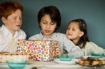 Children looking at wrapped gift at birthday party — Stock Photo