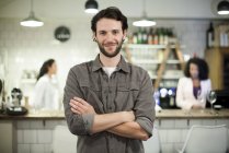 Portrait of cafe owner with coworkers on the background — Stock Photo