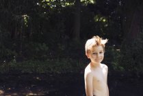Porträt eines Jungen mit nacktem Oberkörper, der in die Kamera blickt, mit Fluss im Hintergrund — Stockfoto