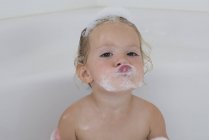 Portrait of funny little girl taking bath with foam — Stock Photo