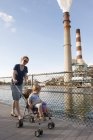 Madre spingendo i bambini nel passeggino vicino alla centrale elettrica — Foto stock