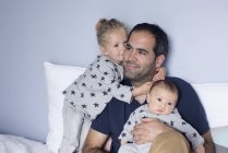 Father with baby boy and young daughter in the bed — Stock Photo