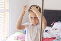 Bambino che fissa i capelli davanti allo specchio — Foto stock