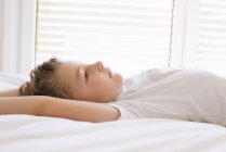 Seitenansicht des Jungen, der sich auf dem Bett entspannt — Stockfoto