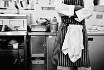 Шеф-повар со сложенными руками стоит на коммерческой кухне — стоковое фото