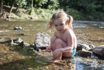 Little girl playing in shallow stream — Stock Photo