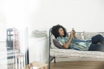Frau schreibt SMS, während sie sich zu Hause entspannt — Stockfoto