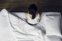 Vista aérea da mulher sentada na borda da cama — Fotografia de Stock