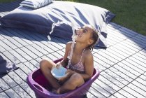 Mädchen sitzt im Eimer und spielt mit Wasser — Stockfoto