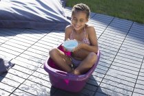 Menina sentada no balde e brincando com a água — Fotografia de Stock