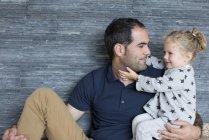 Portrait of father and young daughter against wooden wall — Stock Photo