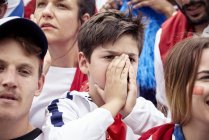 Jovem fã de futebol cobrindo rosto durante jogo de futebol — Fotografia de Stock