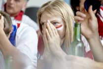 Frau hält enttäuscht die Hände über dem Gesicht, während sie zu Hause ein Sportspiel verfolgt — Stockfoto