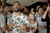 Sports enthusiasts excitedly watching match in bar — Stock Photo