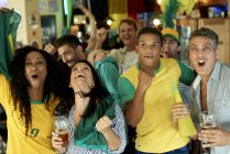 Happy Brazilian soccer fans watching match together at pub — Stock Photo