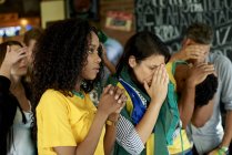 Грустные бразильские футбольные фанаты смотрят матч вместе в пабе — стоковое фото
