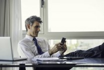 Чоловік використовує смартфон в офісі — стокове фото