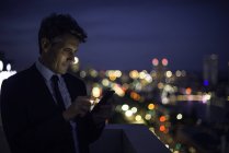 Бизнесмен на крыше высотного здания с помощью мобильного телефона — стоковое фото
