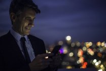Businessman on high rise rooftop using mobile phone — Stock Photo