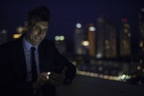Бізнесмен на даху висотного підйому за допомогою мобільного телефону — стокове фото
