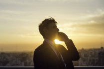 Mann telefoniert mit Handy, Hintergrundbeleuchtung durch untergehende Sonne — Stockfoto
