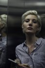Frau benutzt Smartphone im Aufzug — Stockfoto