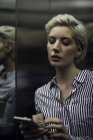 Mujer usando teléfono inteligente en ascensor - foto de stock