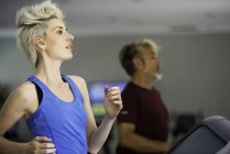 Woman and man exercising on treadmills — Stock Photo