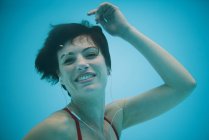 Porträt einer lächelnden Frau, die unter Wasser Kopfhörer hört — Stockfoto