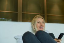 Зріла жінка сміється під час перегляду телевізора — стокове фото