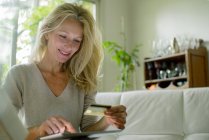 Mujer madura usando la mesa digital para comprar en línea - foto de stock