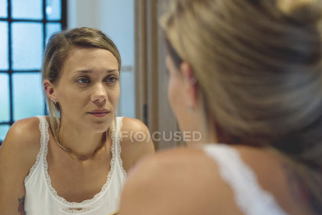 Жінка дивиться на себе у дзеркало у ванній — стокове фото